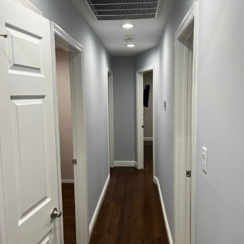 A long hallway with wooden floors and white doors