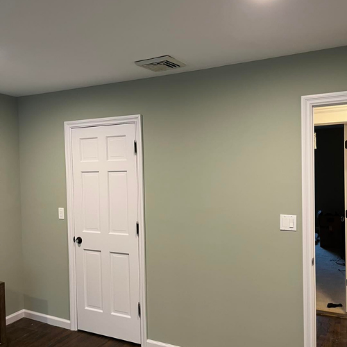 A bedroom with green walls and white doors.