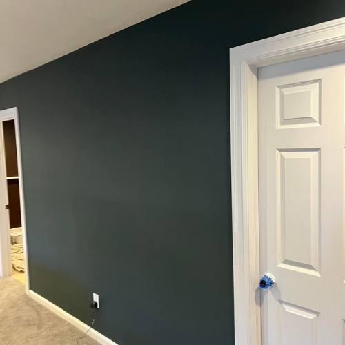 A hallway with a blue wall and a white door.