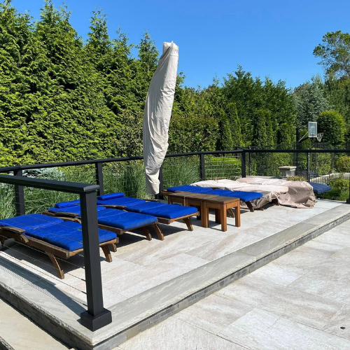 A patio with blue chairs and an umbrella on a sunny day