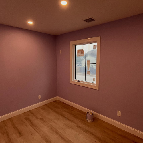 An empty room with purple walls and a window.