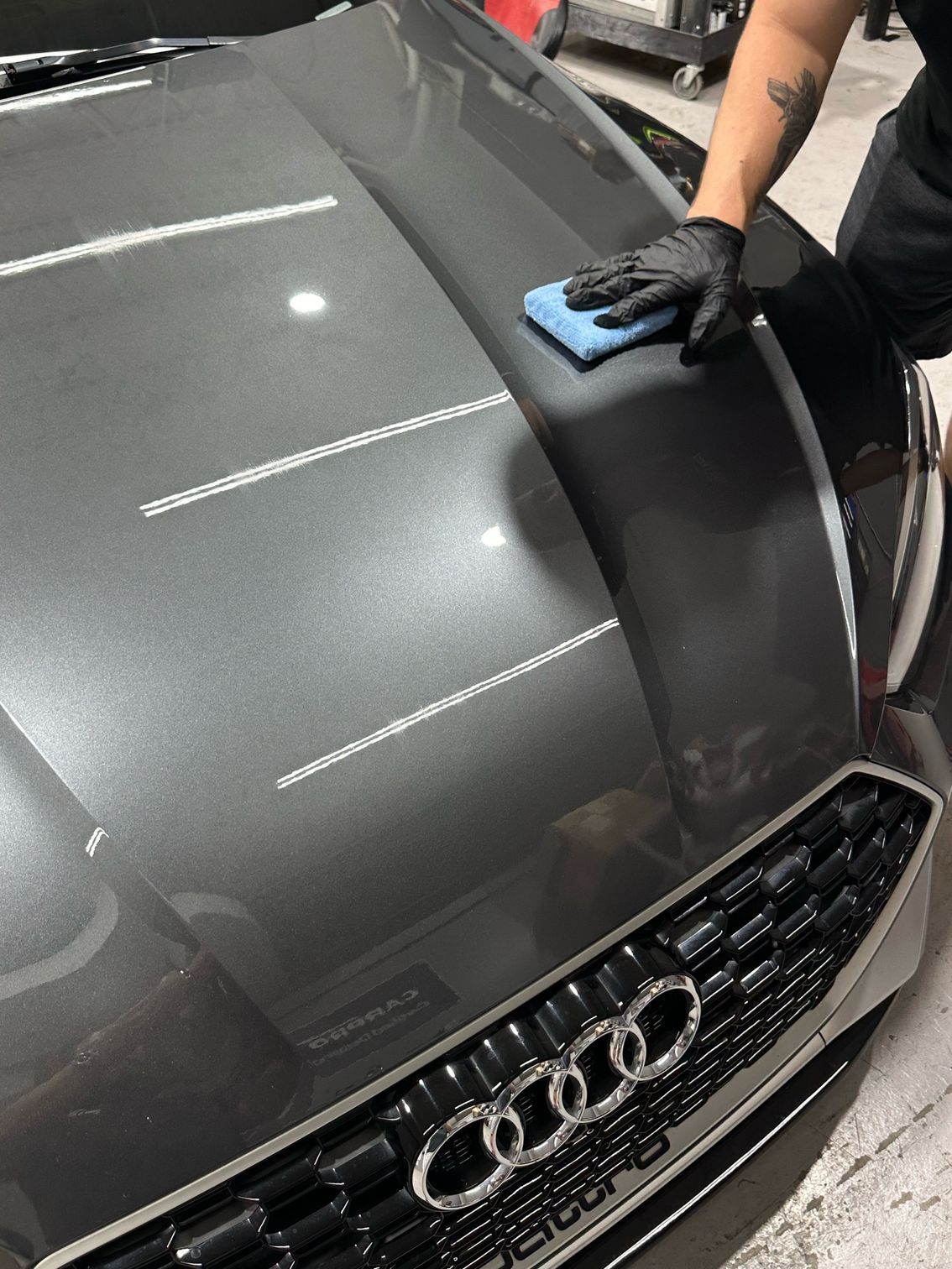 A person is cleaning the hood of a car with a cloth.