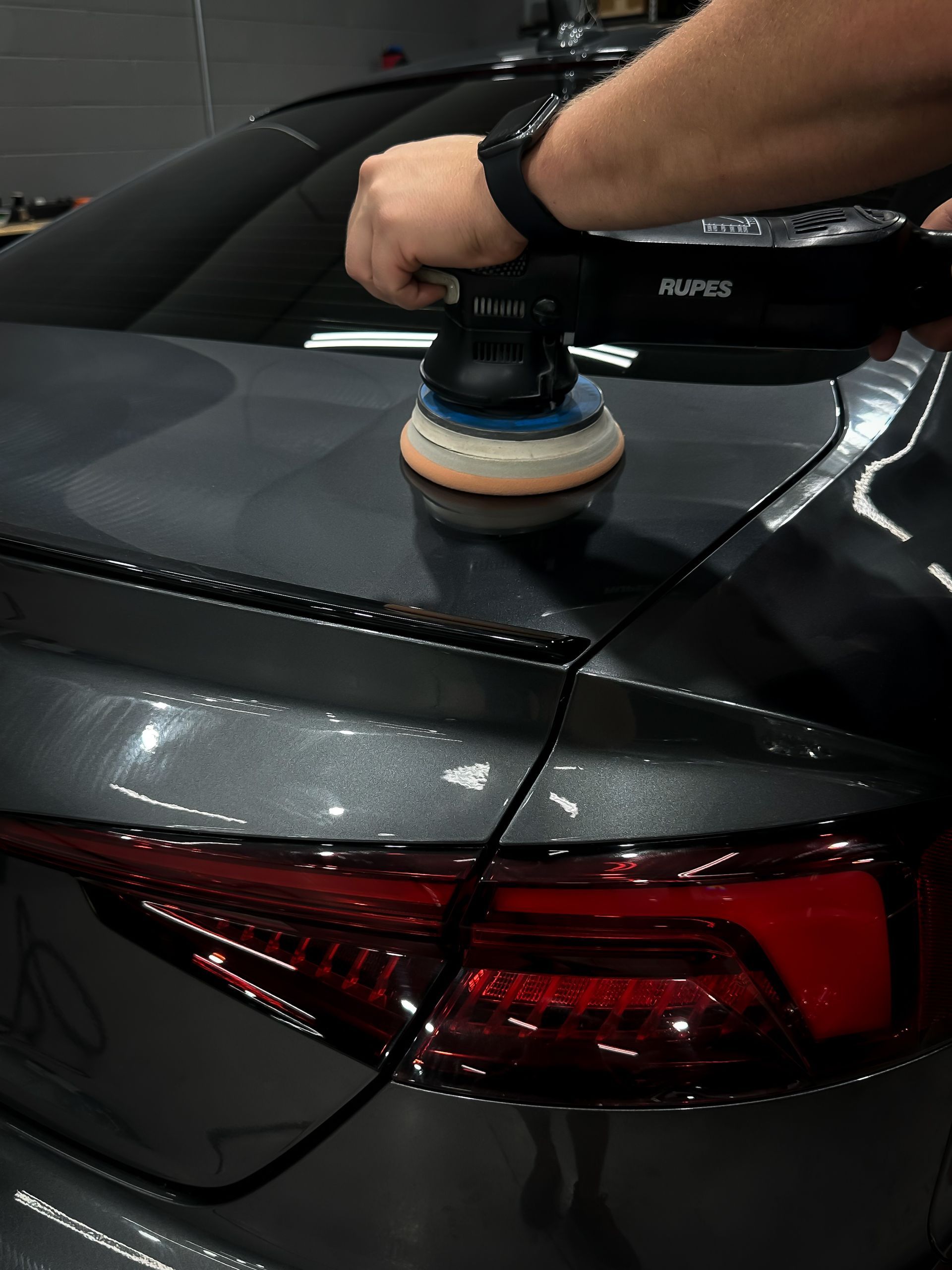 A person is polishing a car with a machine.