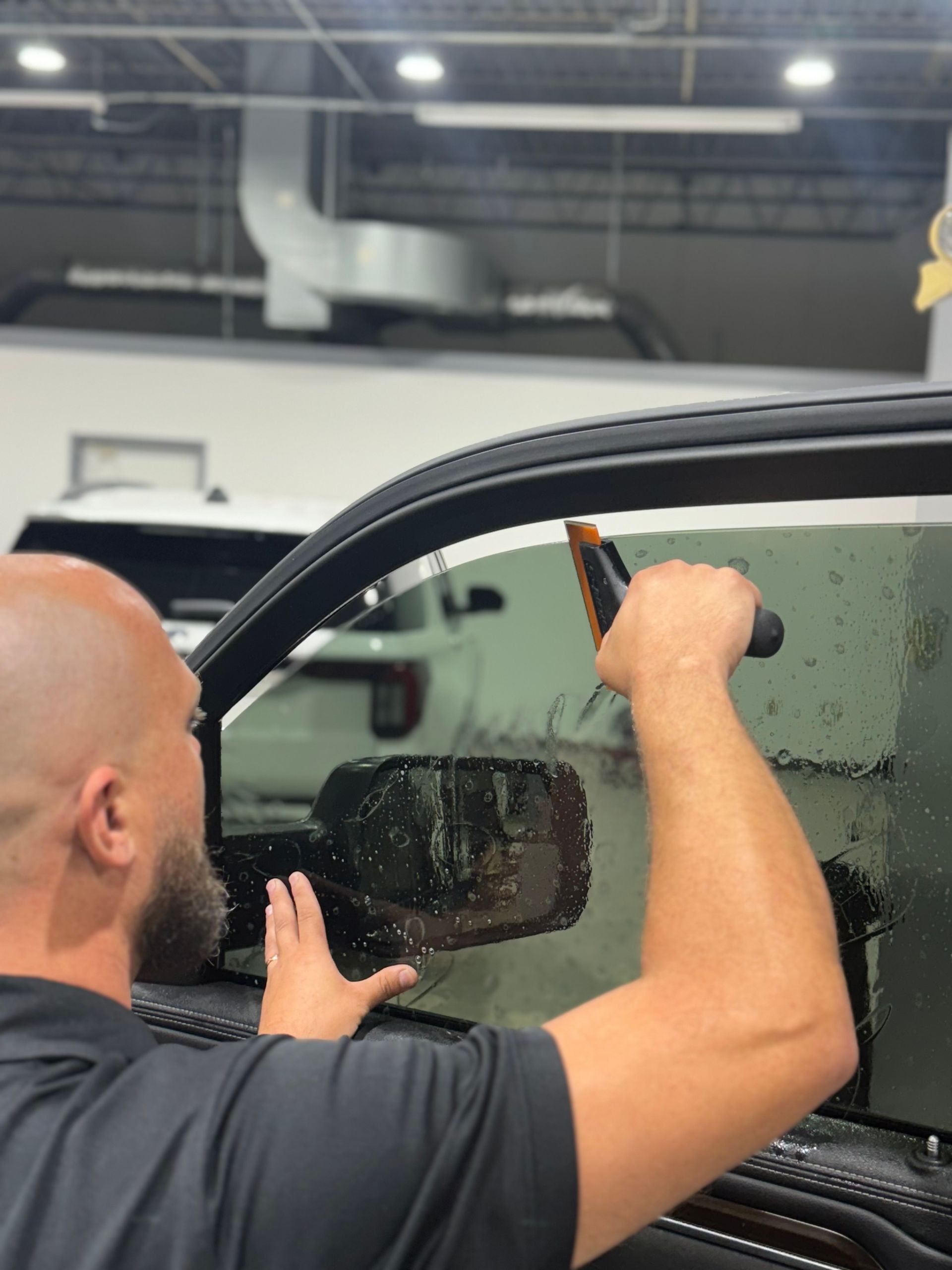 A person is applying window tinting to a car window.