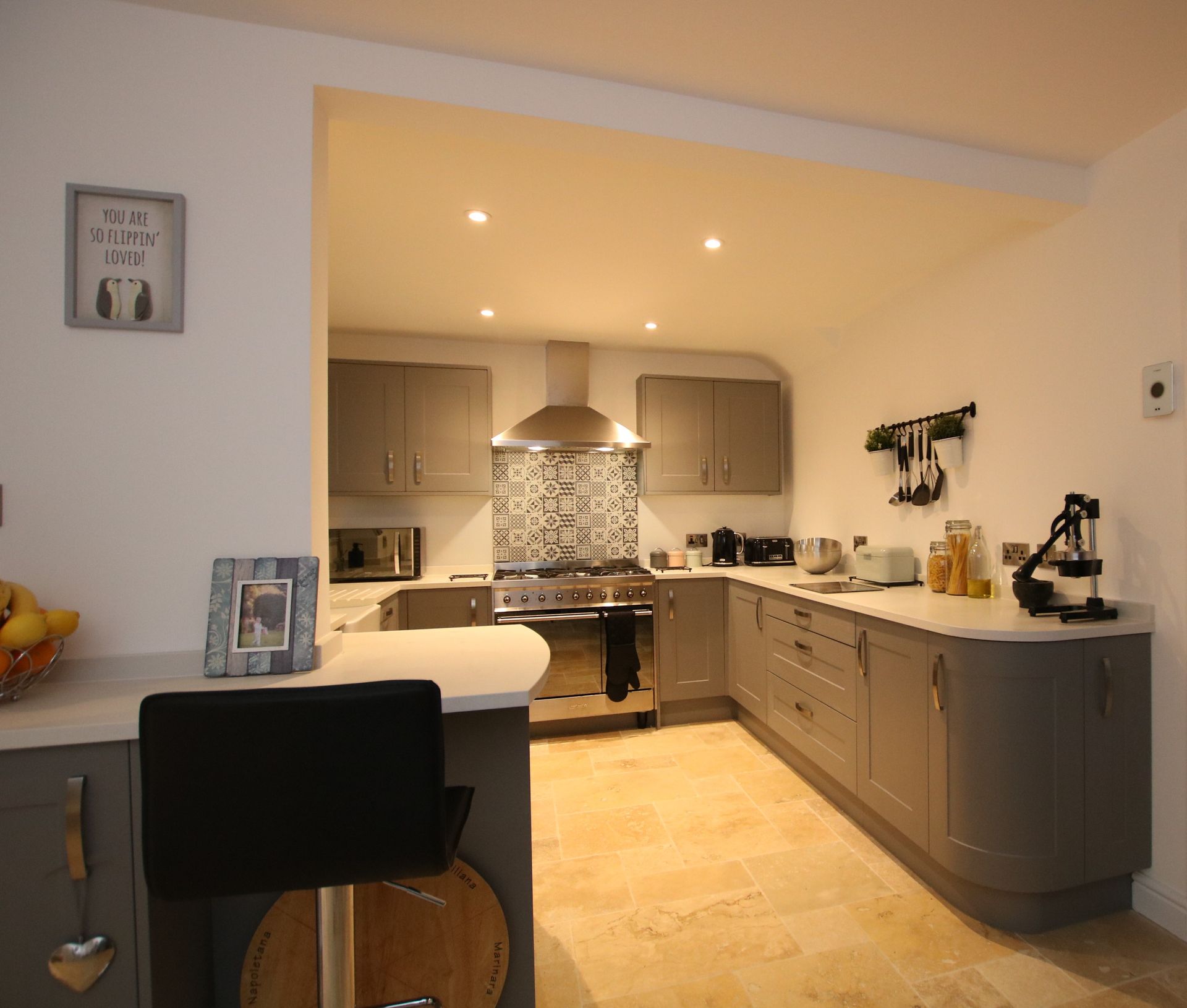 Modern kitchen with gray cabinets, stainless steel appliances, and a curved countertop.