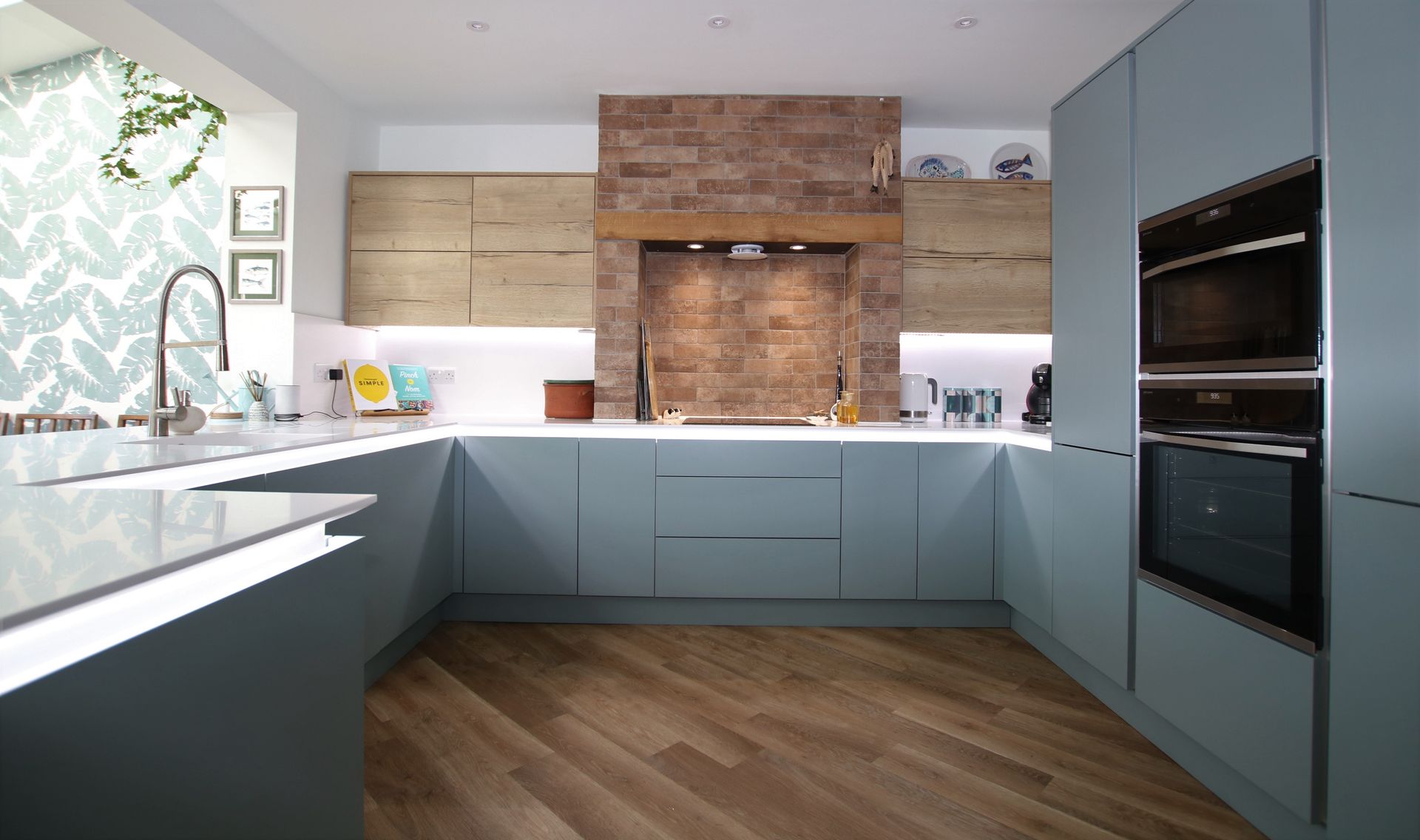 Modern kitchen with blue cabinets, wood floor, and brick range hood.