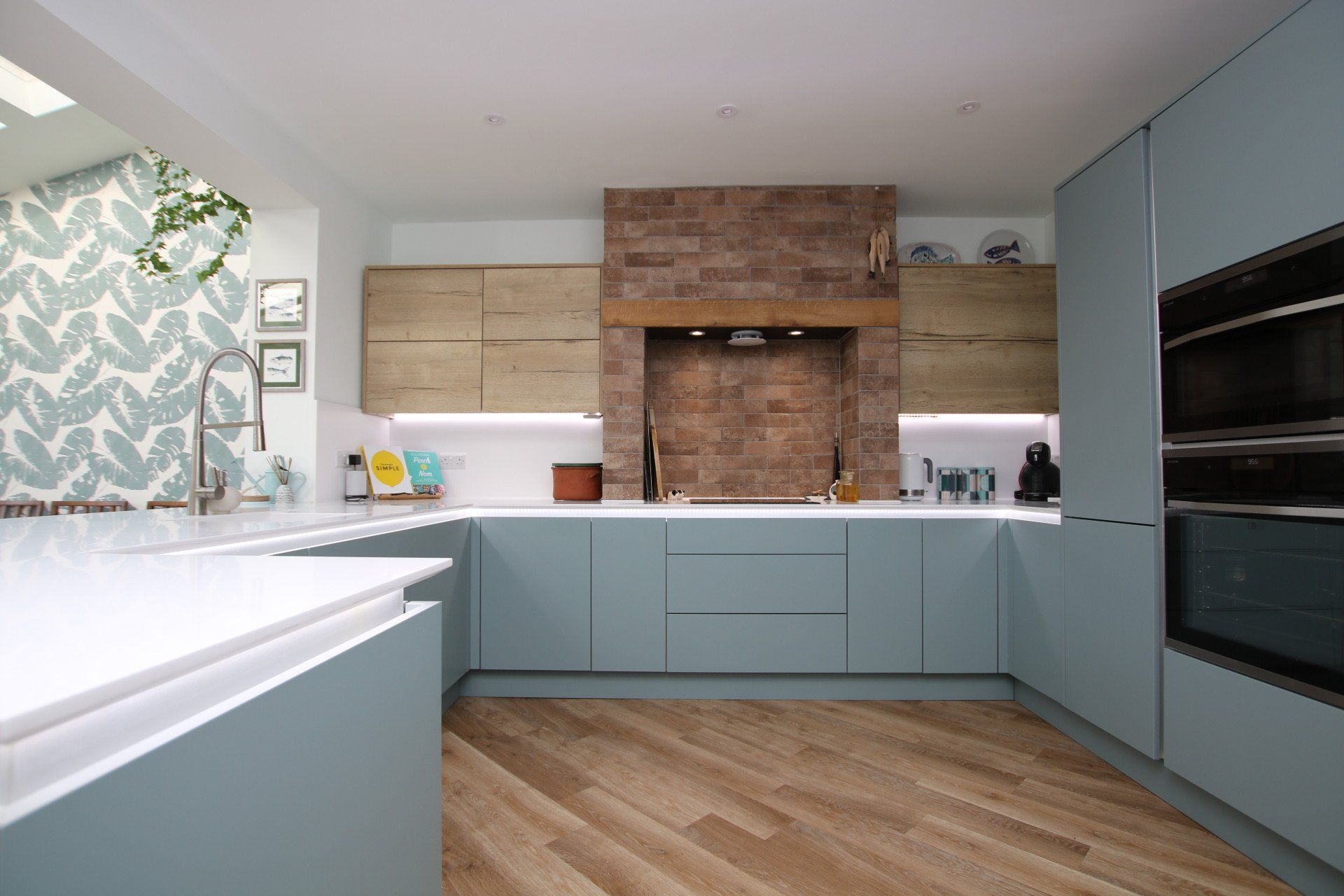 Modern kitchen with light blue cabinets, wood accents, and brick wall.