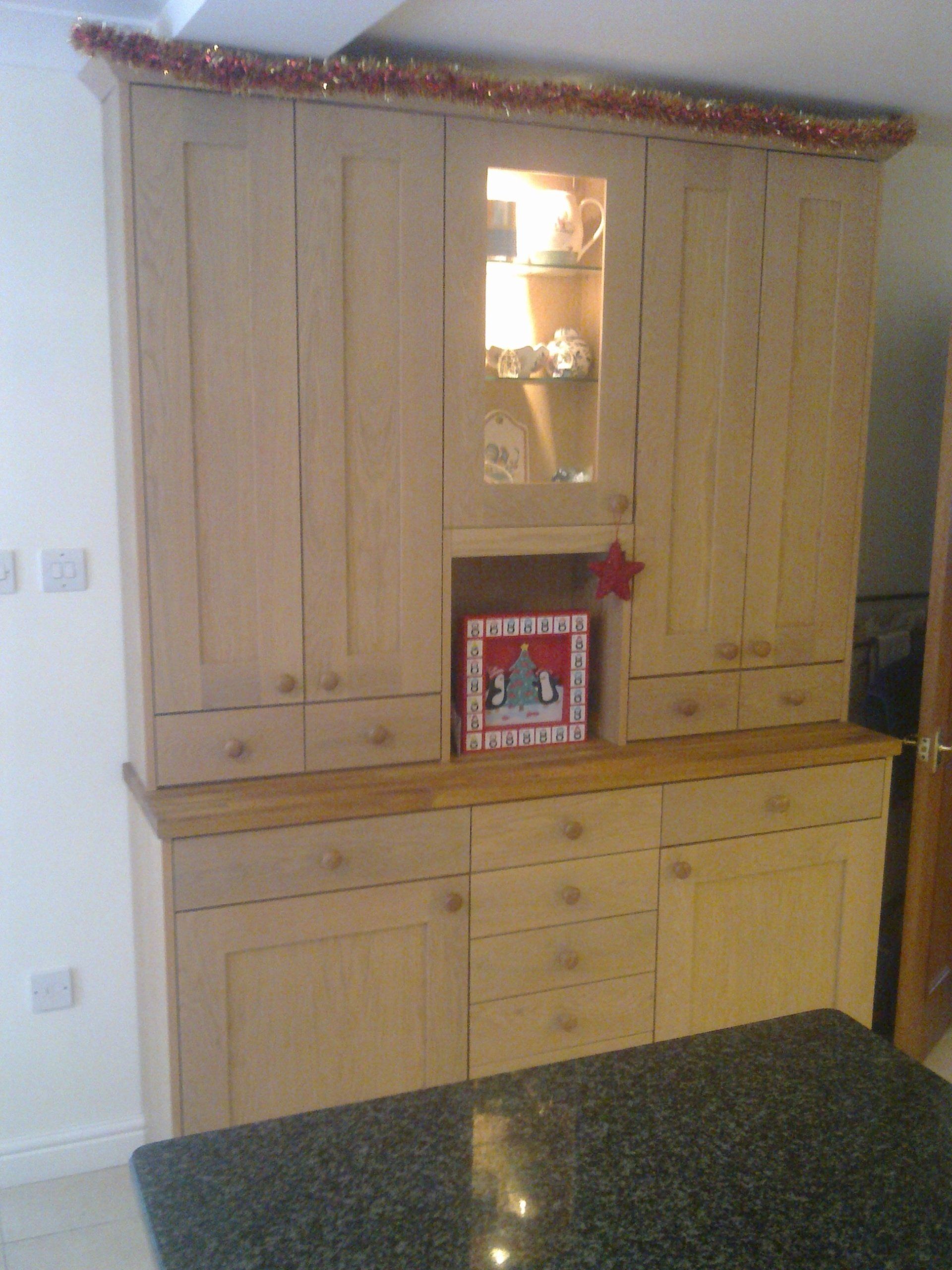 Wooden kitchen cabinets with built-in glass display cabinet and countertop, decorated with red garland.