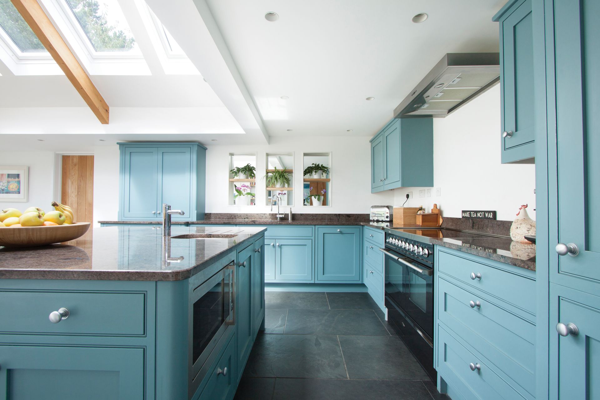 Spacious blue kitchen with granite countertops, stainless steel appliances, and skylights.