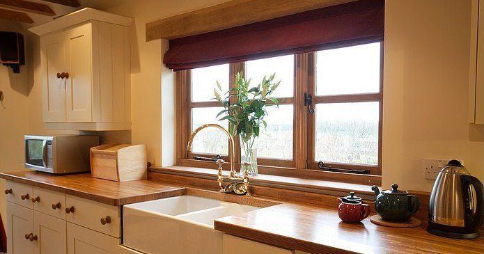 Kitchen with a window above a sink, wooden countertops, and a microwave.