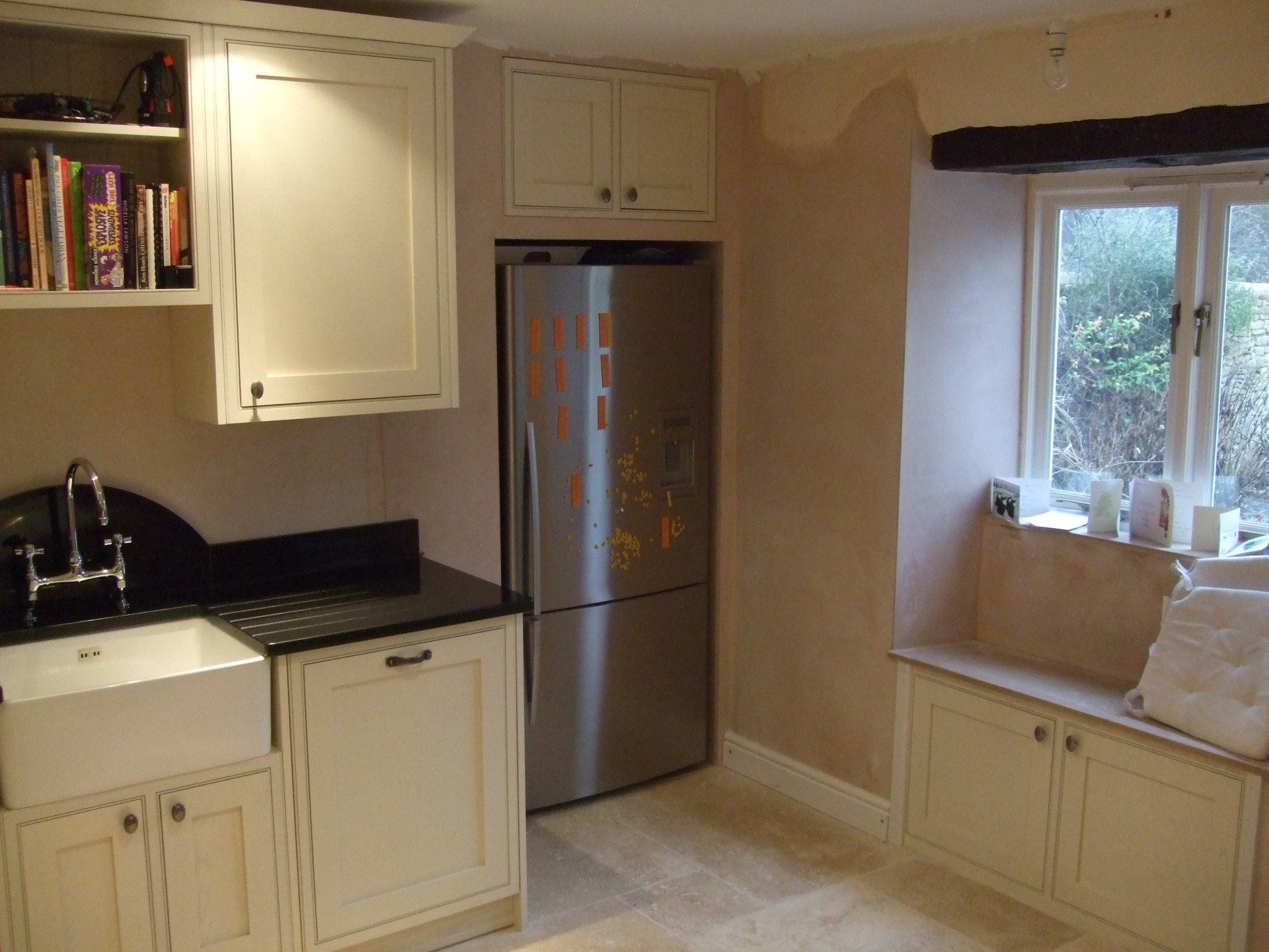 Kitchen with white cabinets, stainless steel refrigerator, sink, and window seat.