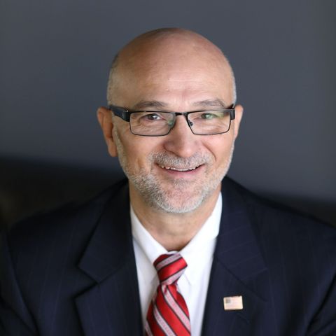 A man in a suit and tie is smiling for the camera