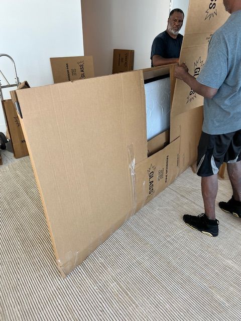 Two movers are carrying boxes out of a van.