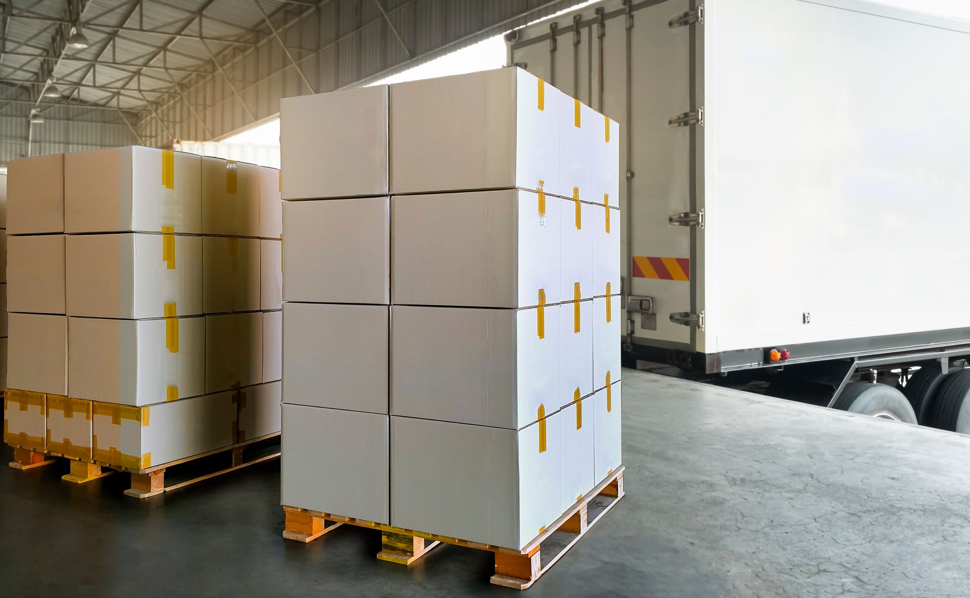 A truck is loading boxes on pallets in a warehouse.