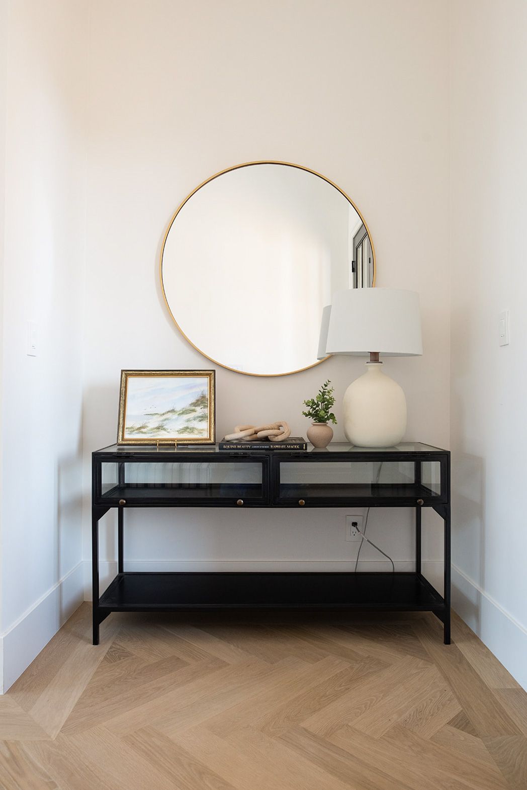 there is a table with a lamp and a mirror on it .