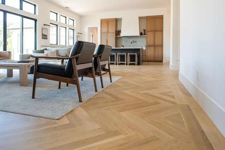 a living room with a wooden floor , chairs , a couch and a table .