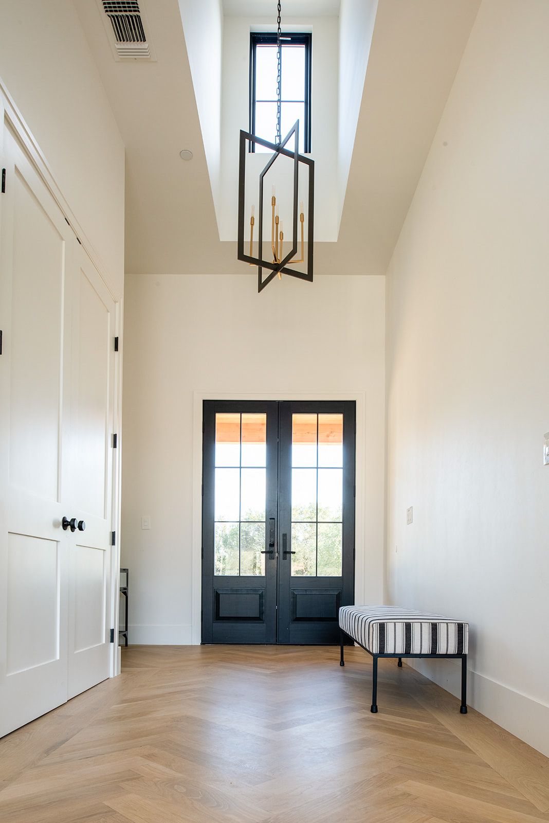 a hallway with a bench and a chandelier hanging from the ceiling .