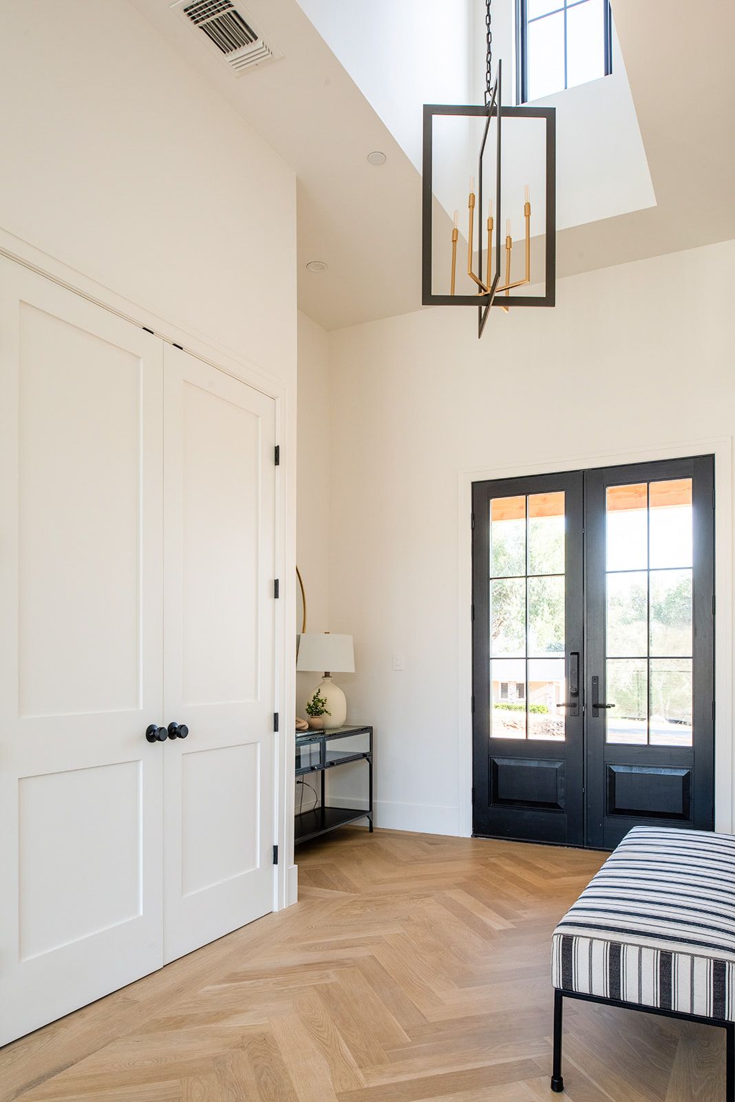 a hallway with a bench and a chandelier hanging from the ceiling .