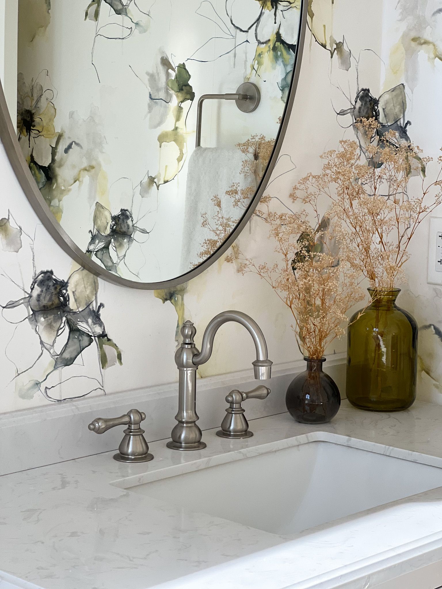 a bathroom sink with a mirror and vases on the counter .