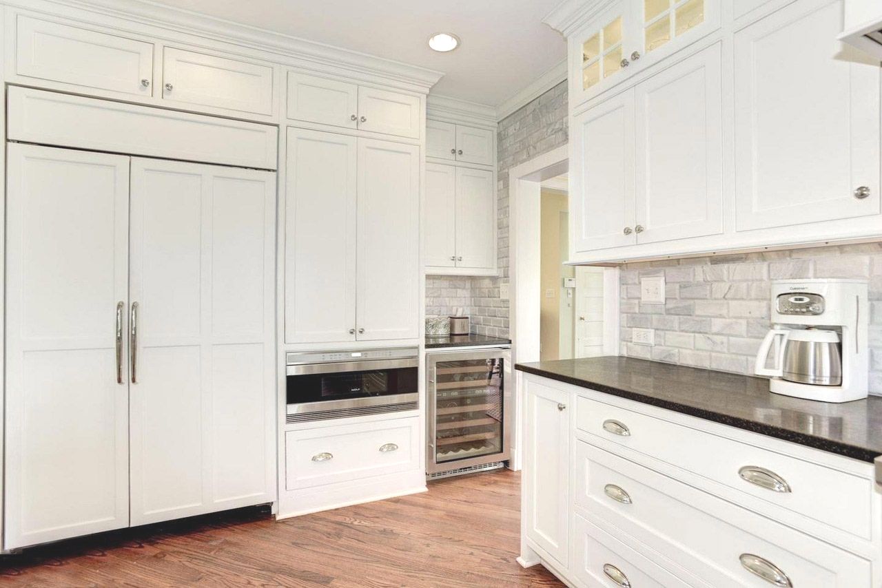 a kitchen with white cabinets , stainless steel appliances , a coffee maker , and a wine cooler .