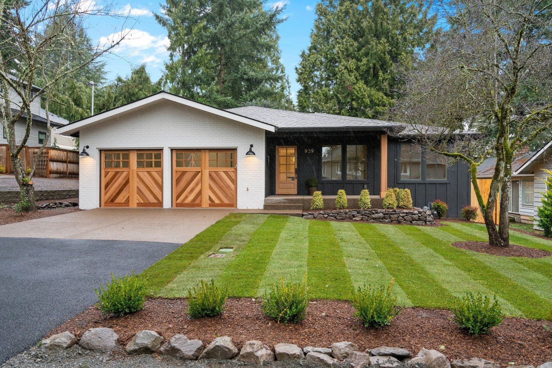 A white house with two garage doors and a lush green lawn.