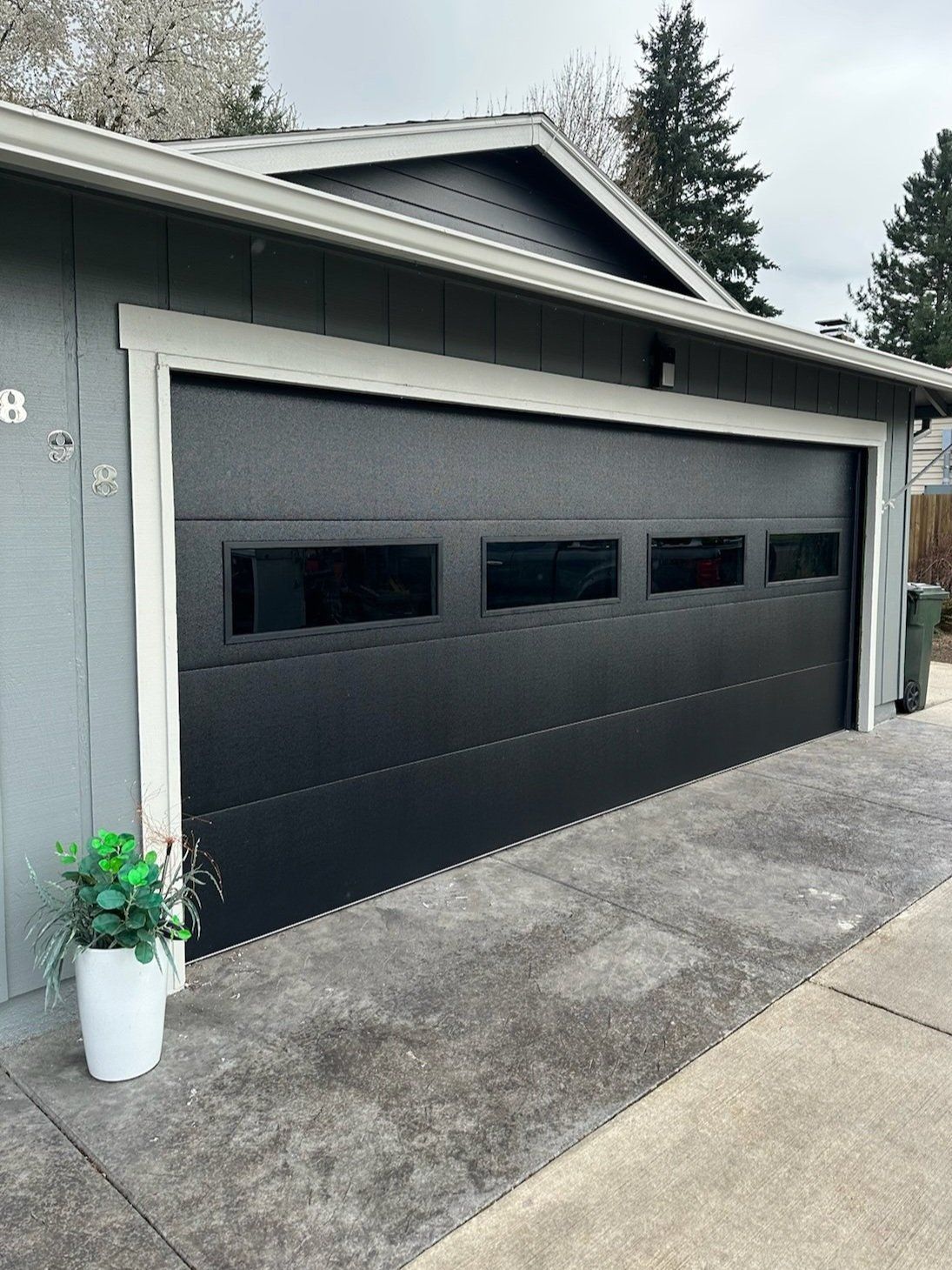 A black garage door with a potted plant in front of it.