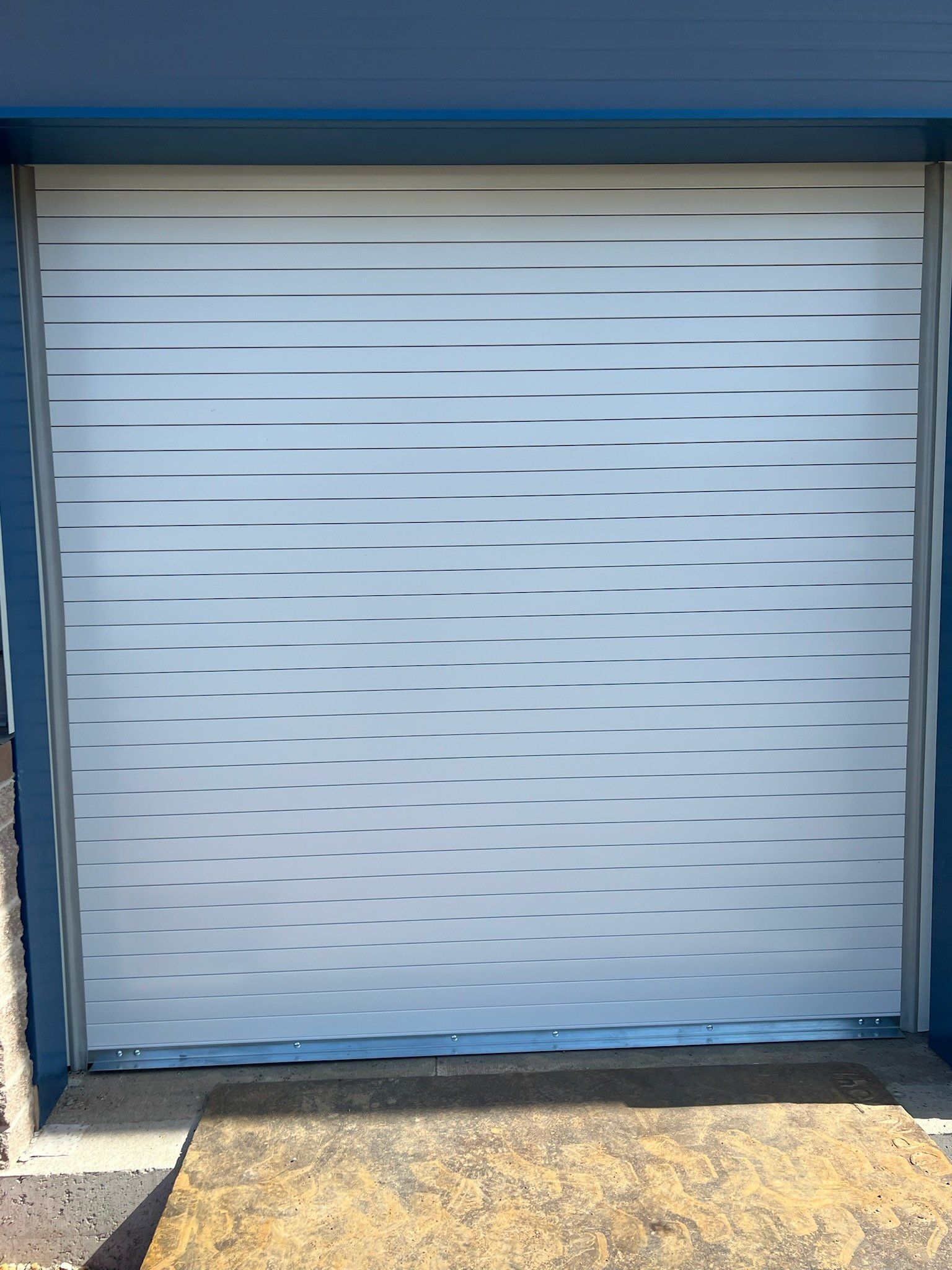 A white garage door with a blue building in the background.