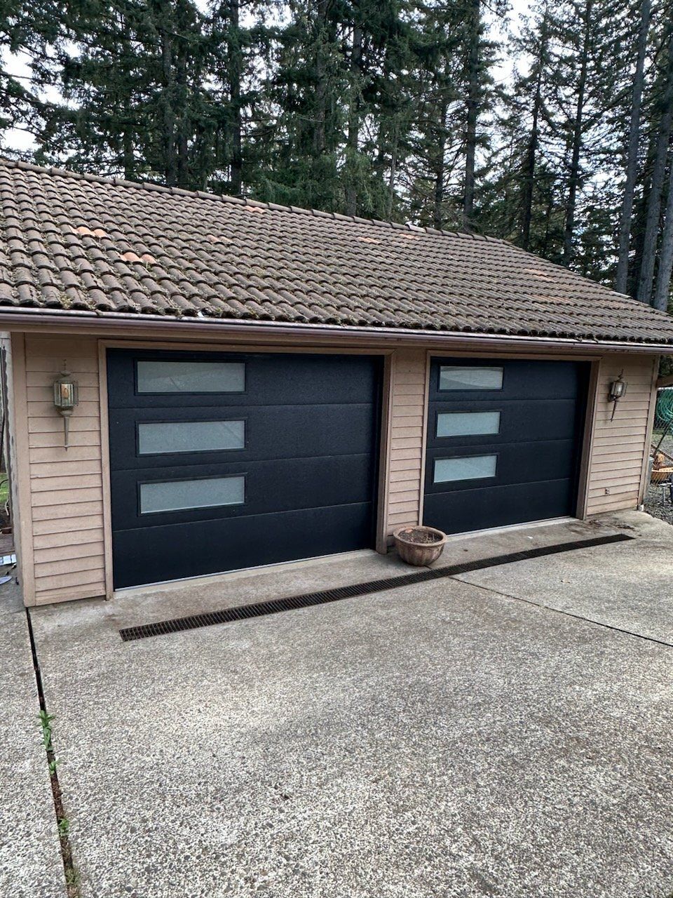 A garage with two black garage doors and a brown roof.