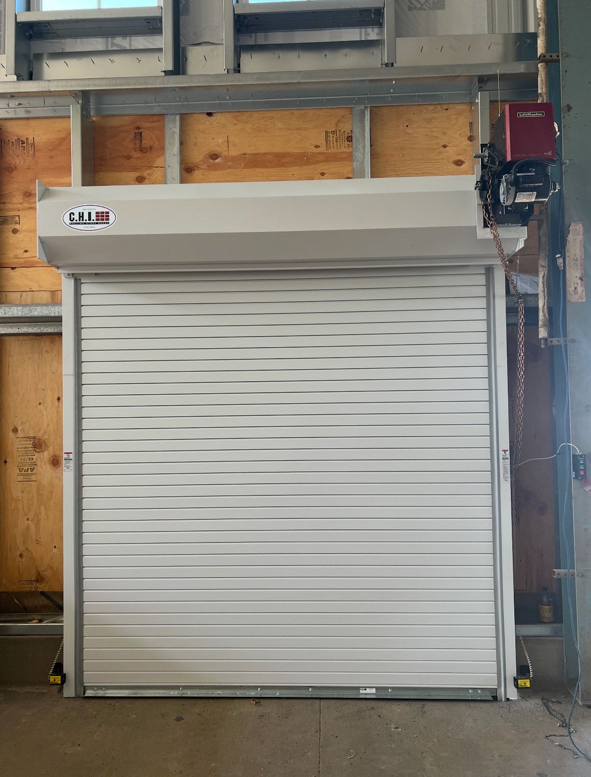 A white garage door is open in a warehouse.