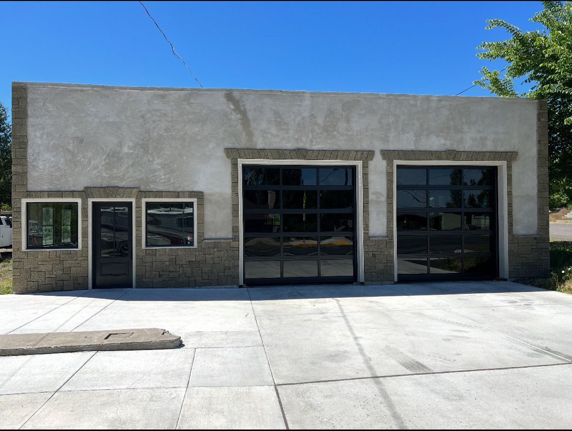 A white garage door with a lot of windows and flowers in front of it.