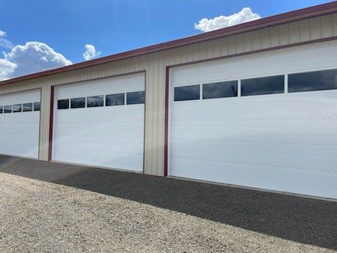 A row of white garage doors on a building.