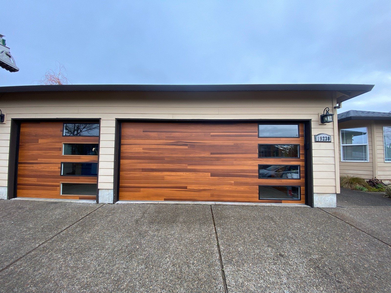 A house with a wooden garage door and a concrete driveway.