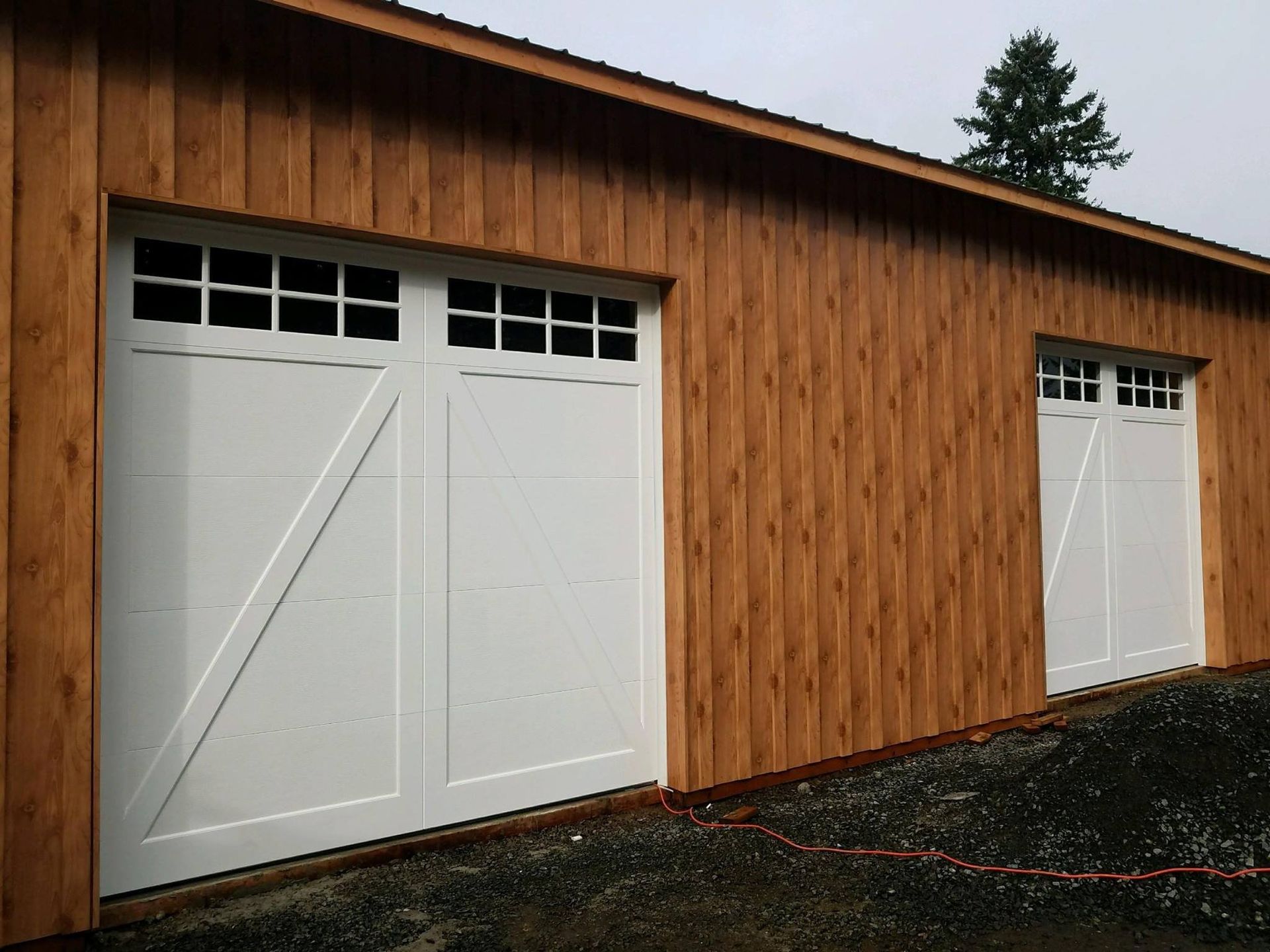 Two white garage doors on a wooden building