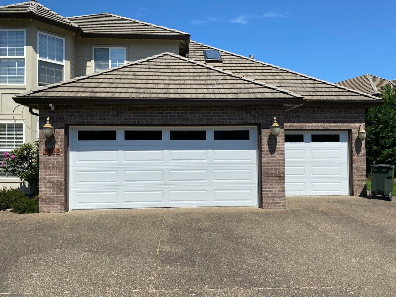 A house with two white garage doors and a brick wall
