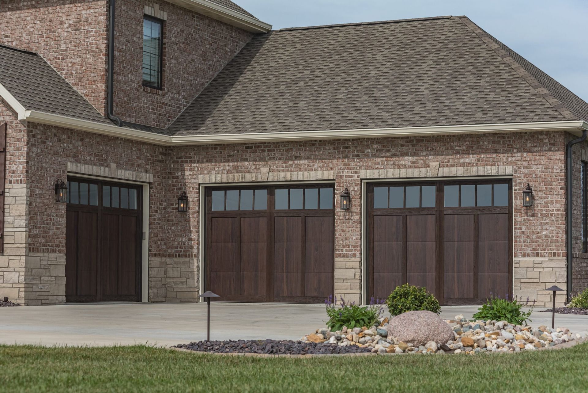 A large brick house with two brown garage doors.