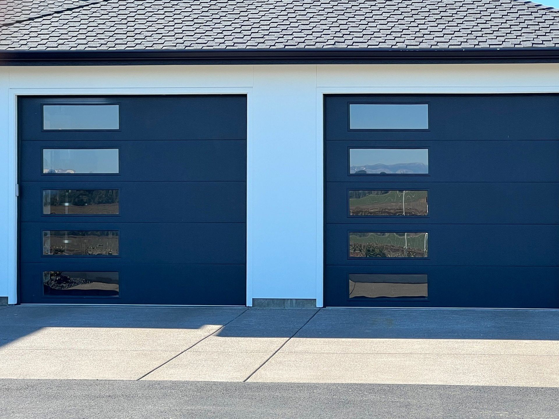 There are two garage doors on the side of a house.