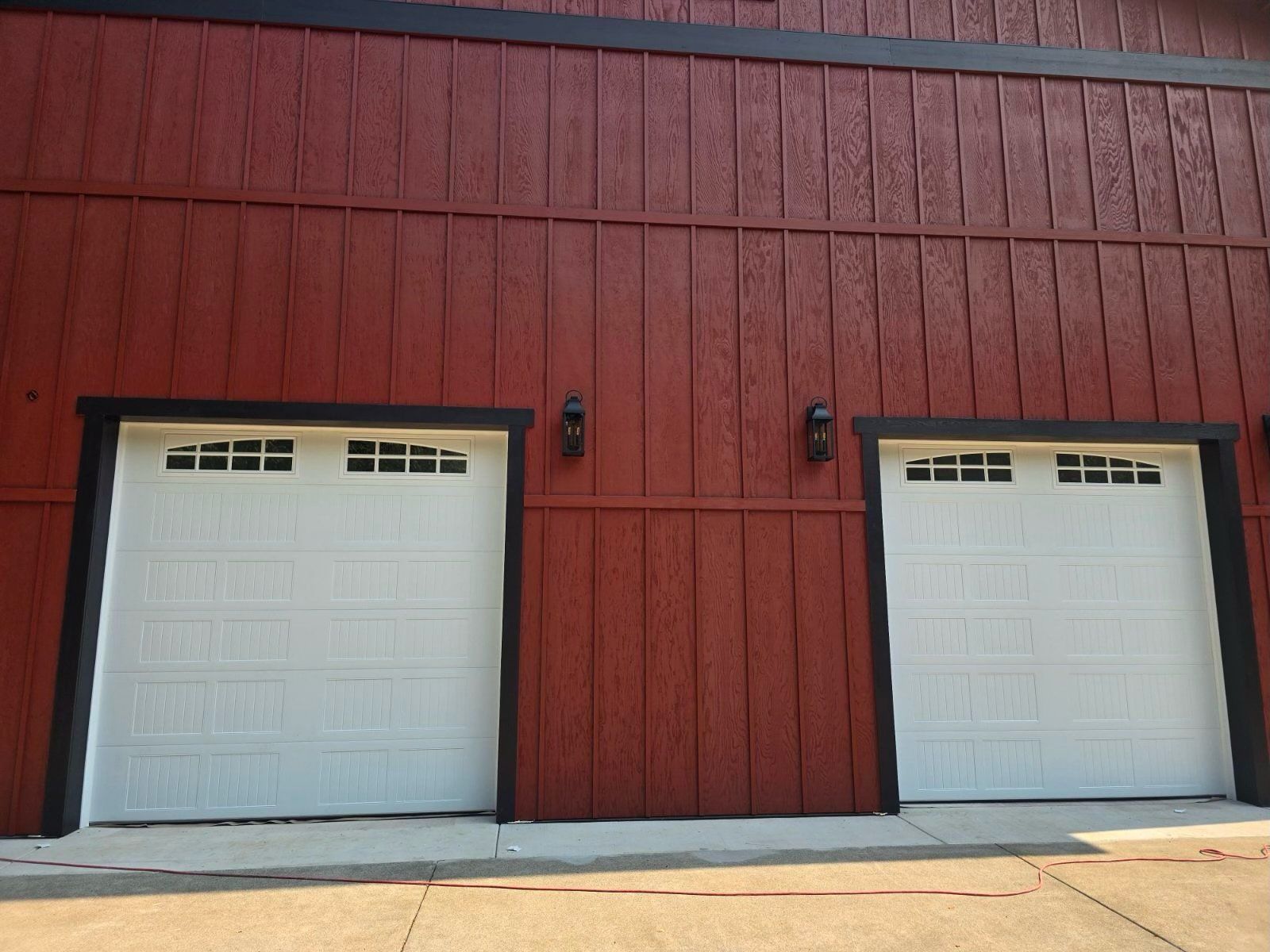There are two garage doors on the side of a red building.