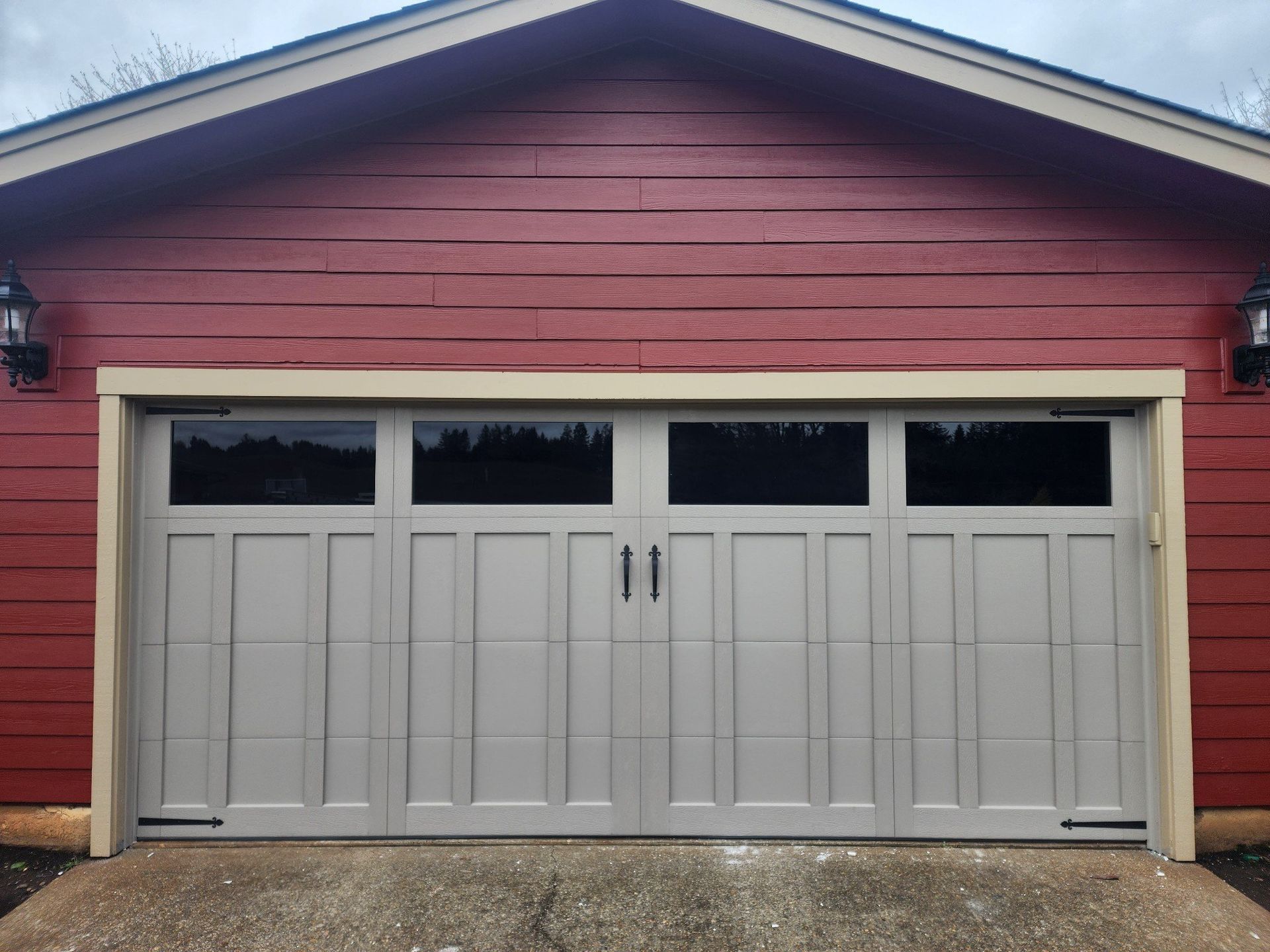 A large white garage door is sitting in front of a red house.