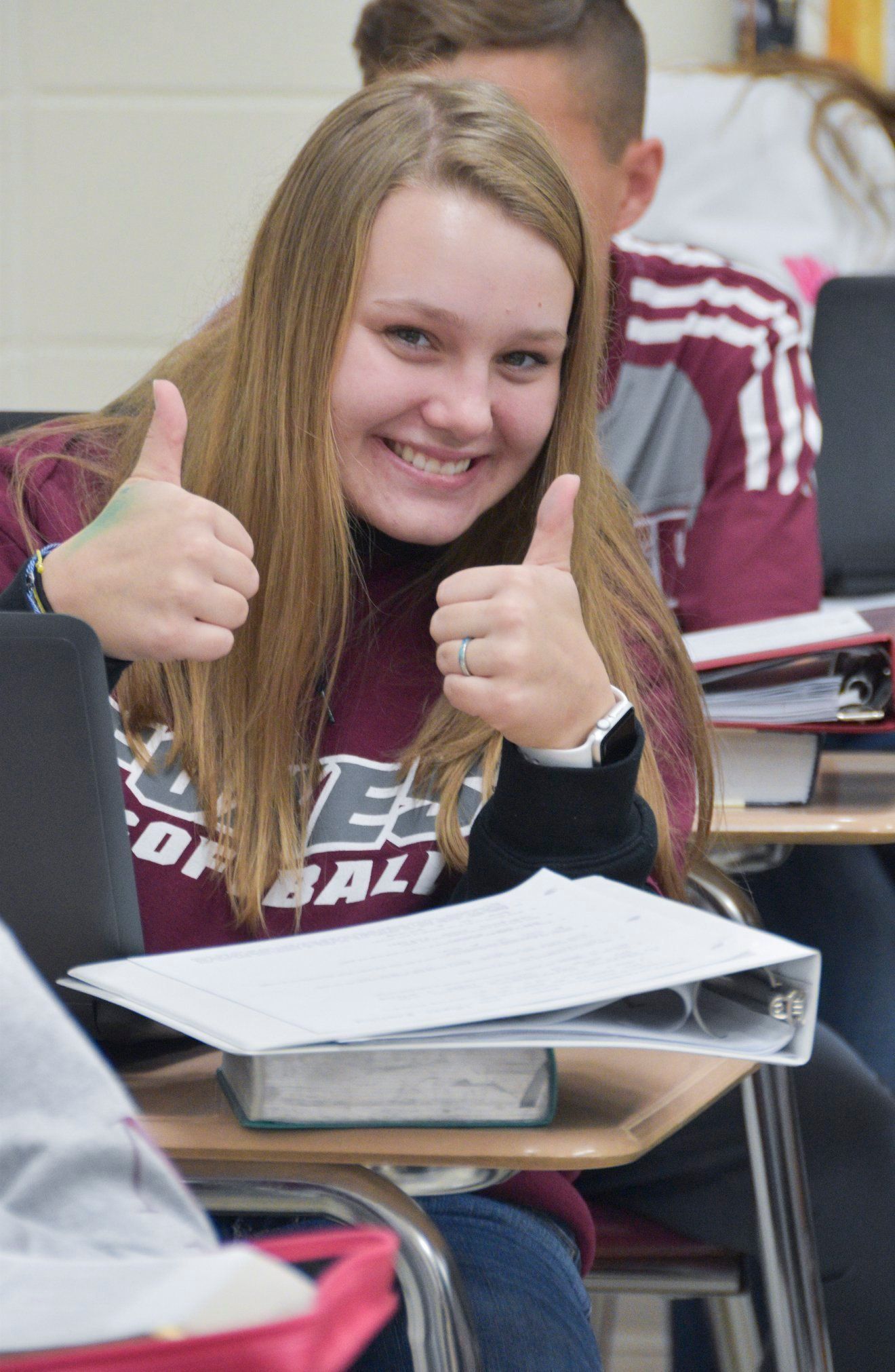 Smiling High School student at desk, giving a thumbs up