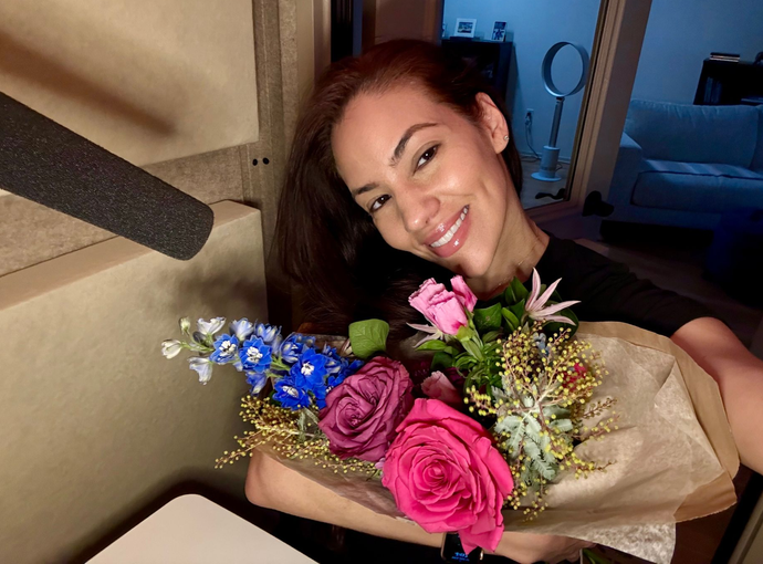Iris in booth smiling holding bouquet of flowers