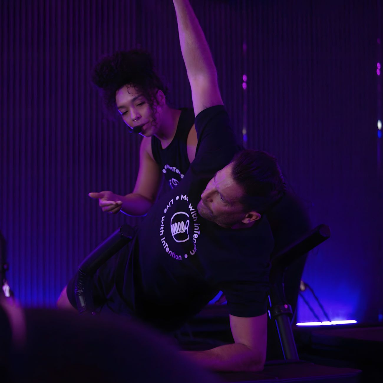 A man doing a side plank while the instructor corrects form