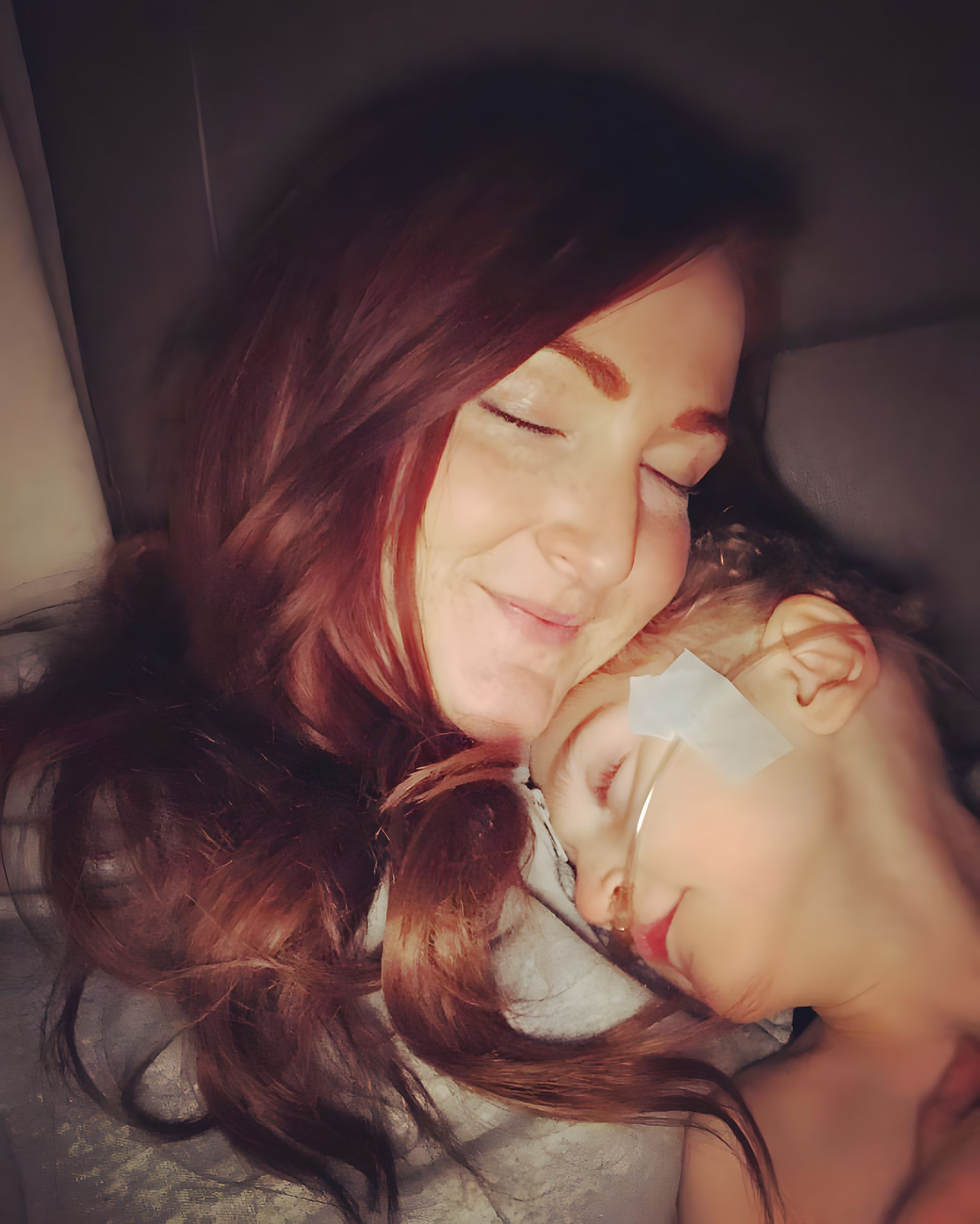 A woman is holding a child who is sleeping on her chest.