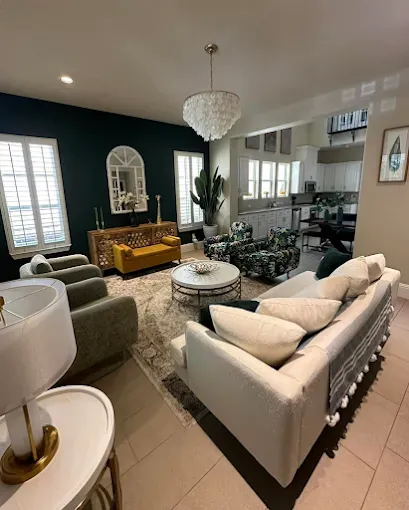 Living room with a dark teal accent wall, white sofa, and a chandelier.