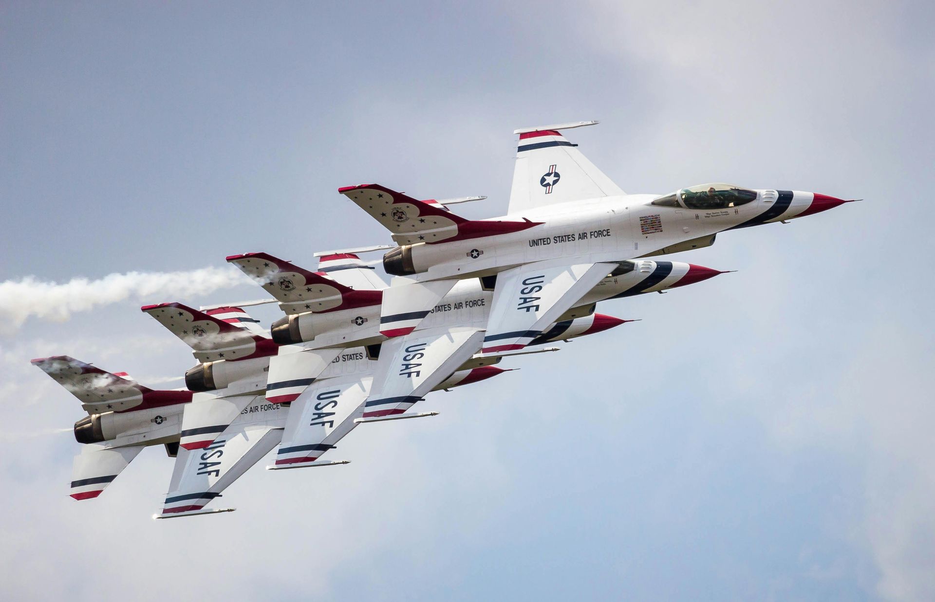 Four fighter jets in tight formation against a cloudy sky