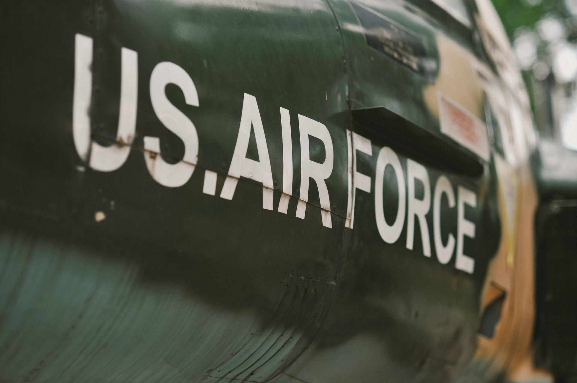 Close-up of a green U.S. Air Force aircraft fuselage with white lettering