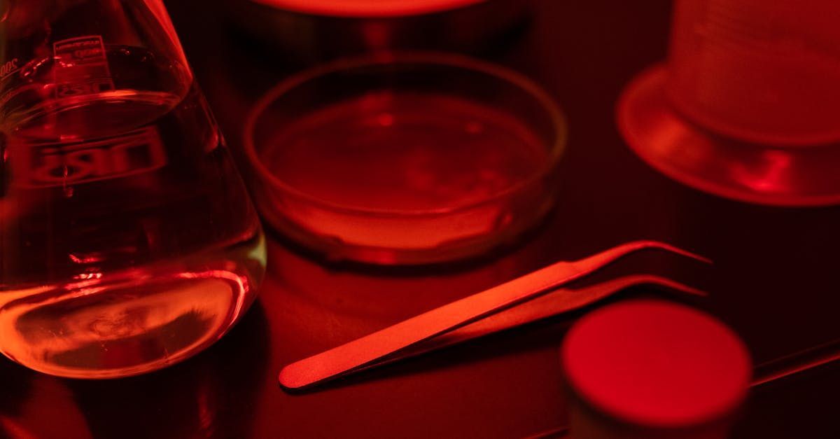 A close up of a glass of beer and a pair of tweezers on a table.