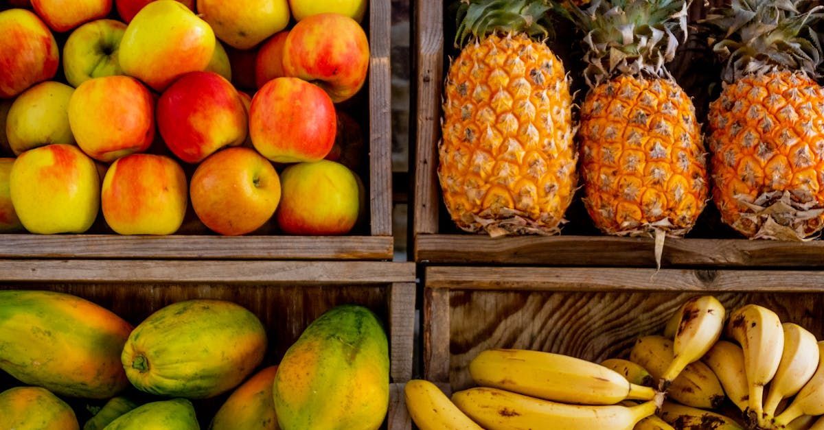 Pineapples , apples , papayas , bananas and mangoes are in wooden crates.