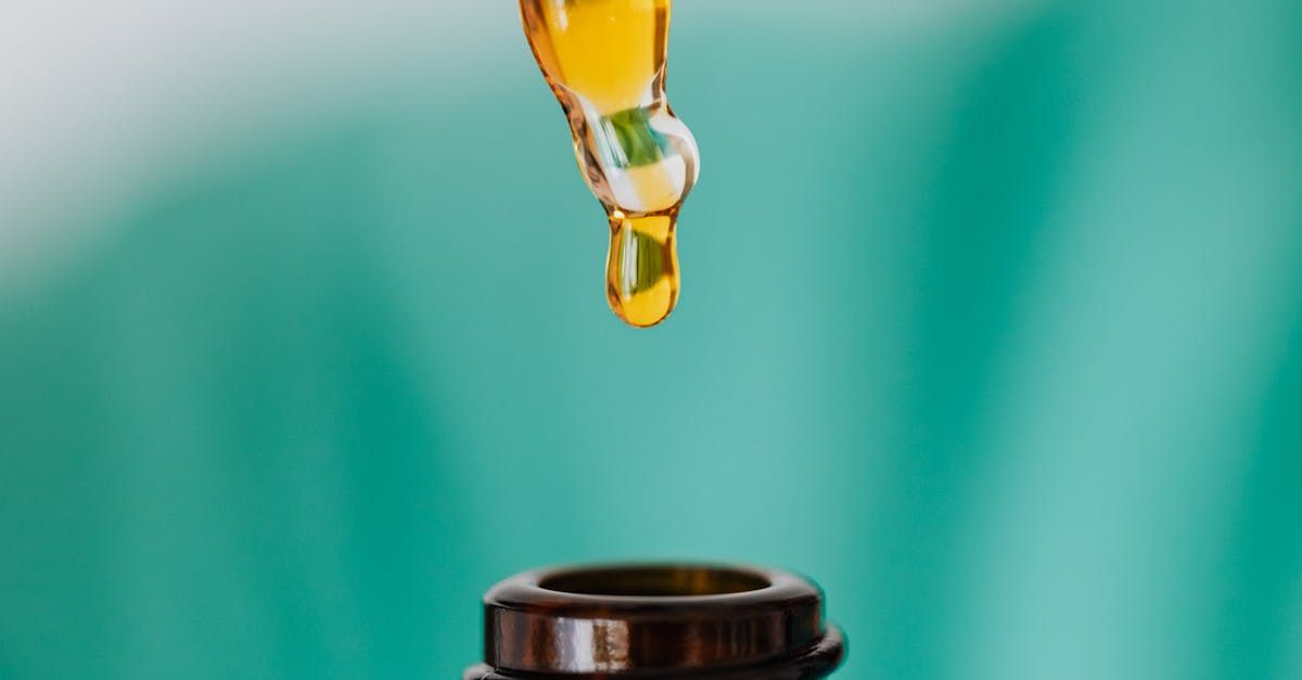 A drop of oil is being poured from a pipette into a bottle.