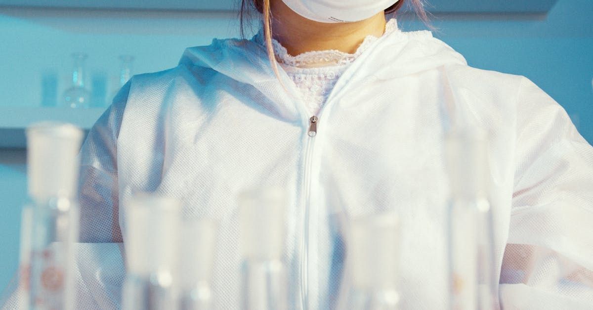 A woman wearing a mask and a protective suit is working in a laboratory.