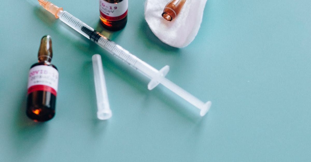 A syringe , bottles and ampoules are on a table.